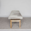 end view of the cream coloured cowhide ottoman bench on a teak wood base by corcovado