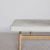 close up end view of the cream coloured cowhide ottoman bench on a teak wood base by corcovado