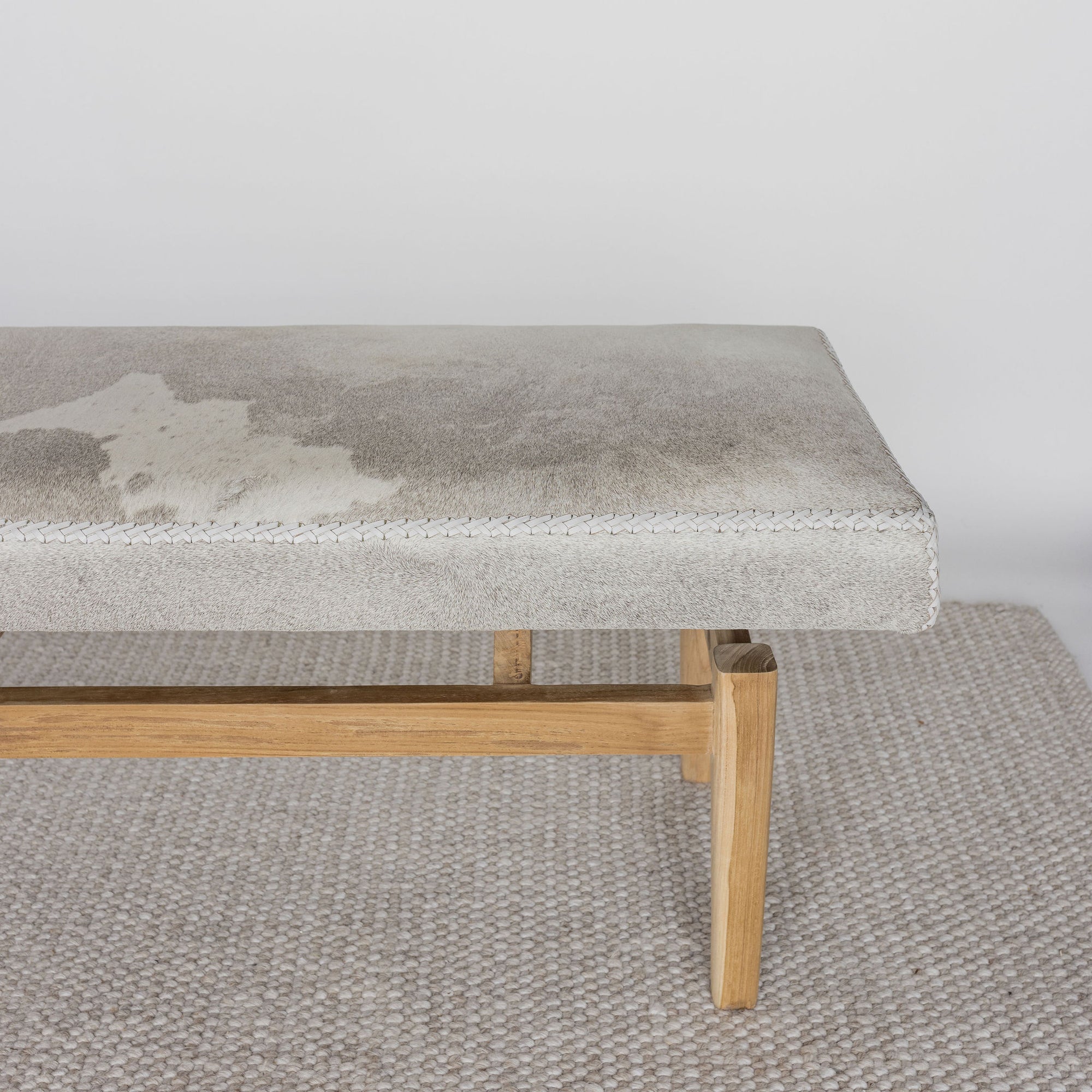 close up view of one end of a cream and grey cowhide ottoman bench seat from corcovado 