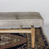 close up end view of a modern cream coloured cowhide bench seat ottoman on top of a turkish rug