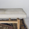 end view close up of a modern cream coloured cowhide bench seat ottoman on top of a turkish rug