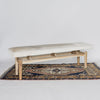 angled view of a modern cream coloured cowhide bench seat ottoman on top of a turkish rug