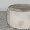 close up view of the light tones and leather stitching on a round cowhide ottoman coffee table