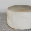 close up photo showing the light tones and leather stitching on a round cowhide ottoman coffee table