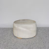 light tones and leather stitching on a round cowhide ottoman coffee table