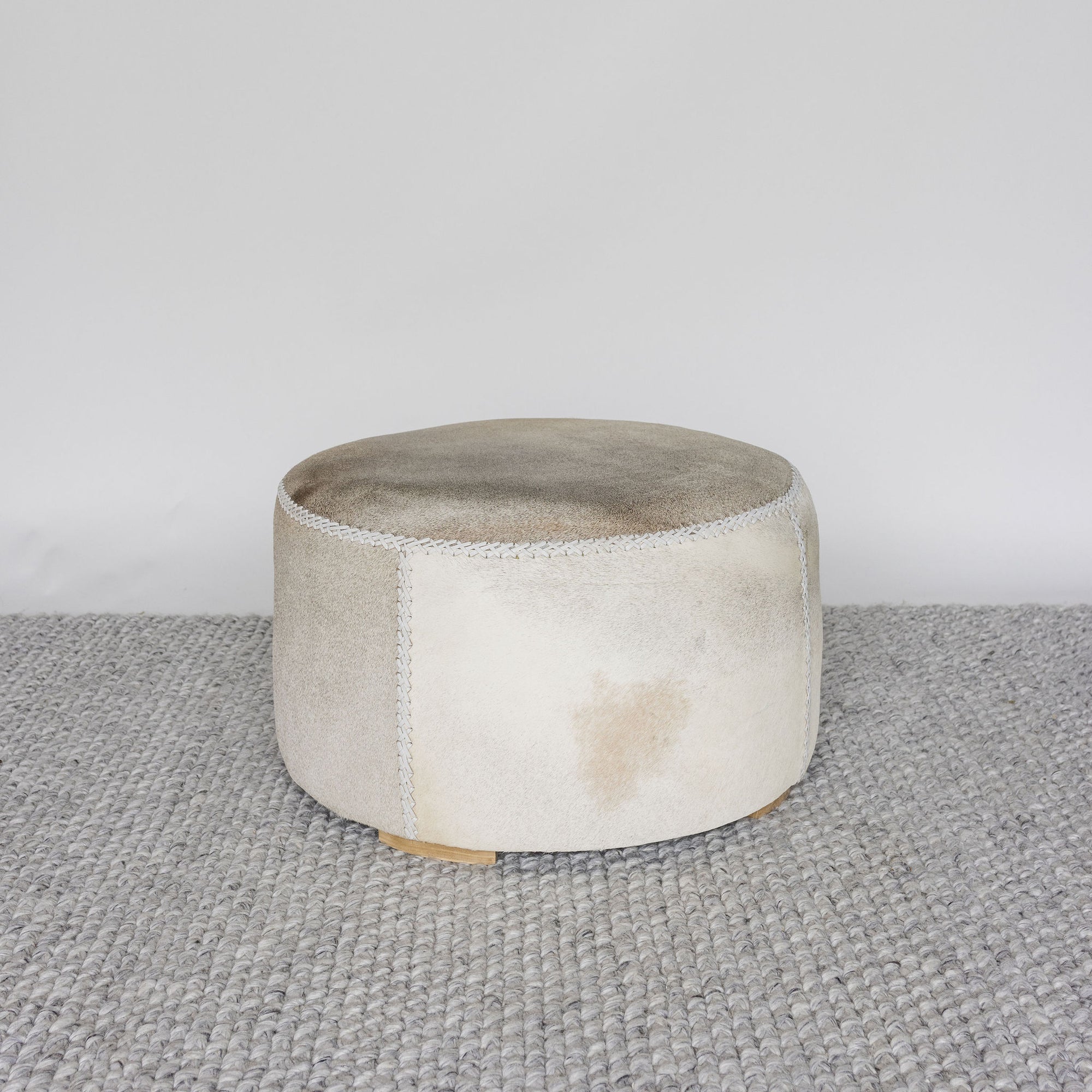 light tones and leather stitching on a round cowhide ottoman coffee table