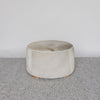 front view of the light tones and leather stitching on a round cowhide ottoman coffee table