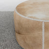 close up view of the front view of a caramel coloured round cowhide ottoman coffee table by Corcovado