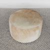 top down view of front view of a caramel coloured round cowhide ottoman coffee table by Corcovado