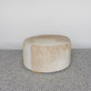 front view of a caramel coloured round cowhide ottoman coffee table by Corcovado