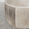 close up showing the leather stitching on the grey and cream round cowhide ottoman coffee table