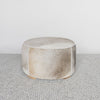 grey and cream round cowhide ottoman coffee table with caramel sections on the hide