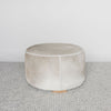 front view of the grey and cream round cowhide ottoman coffee table