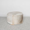 side view of the grey and cream round cowhide ottoman coffee table