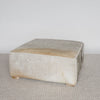 angled corner view of an extra large grey coloured square cowhide ottoman coffee table