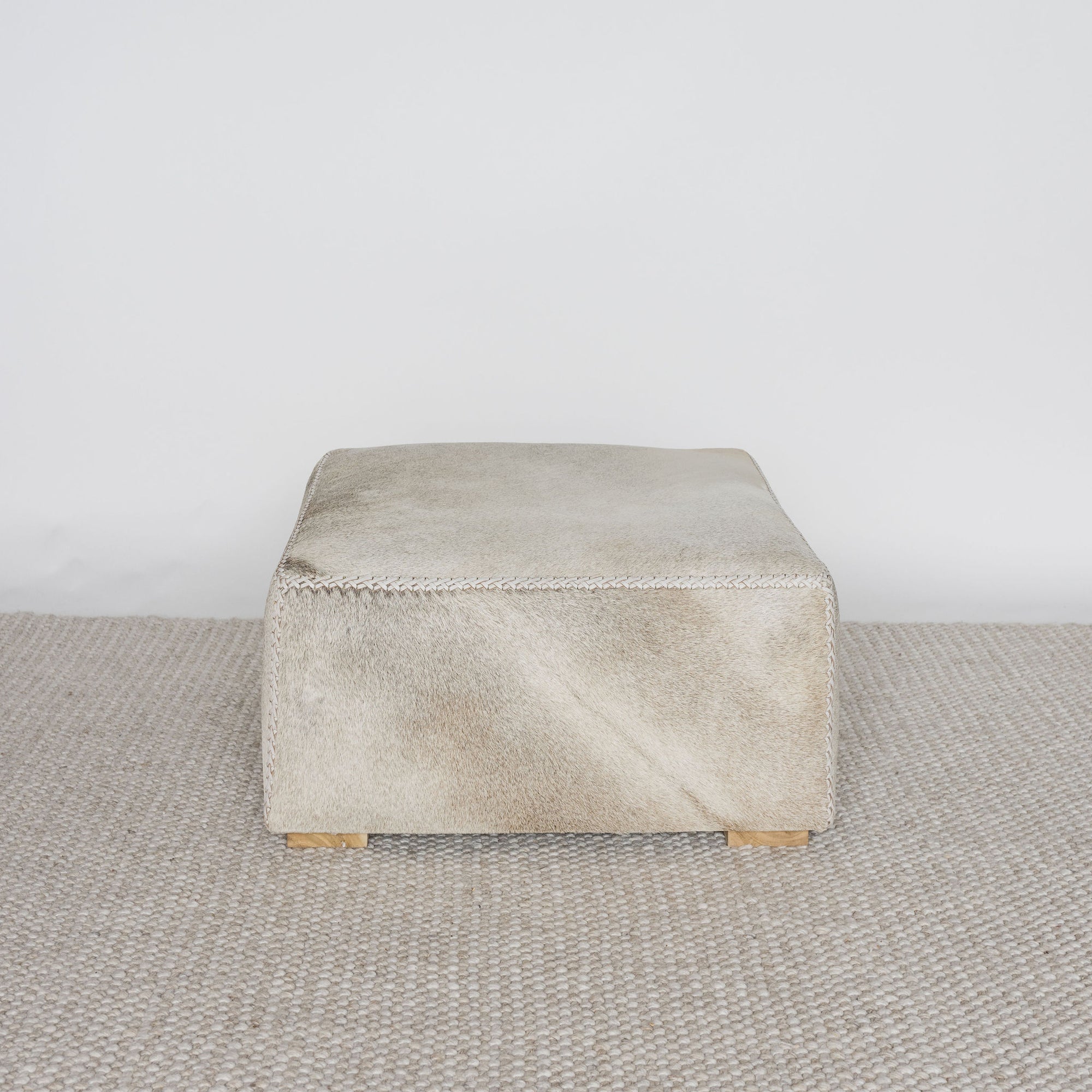 square cowhide ottoman coffee table in natural tones