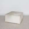 angled view of the square cowhide ottoman coffee table in natural tones