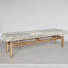 angled view of the long cowhide bench seat with grey and cream coloured cowhide