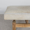 end view of a cowhide bench seat in cream earthy neutral tones