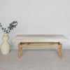 front view of of a cowhide bench seat in cream earthy neutral tones together with an organic tall vase