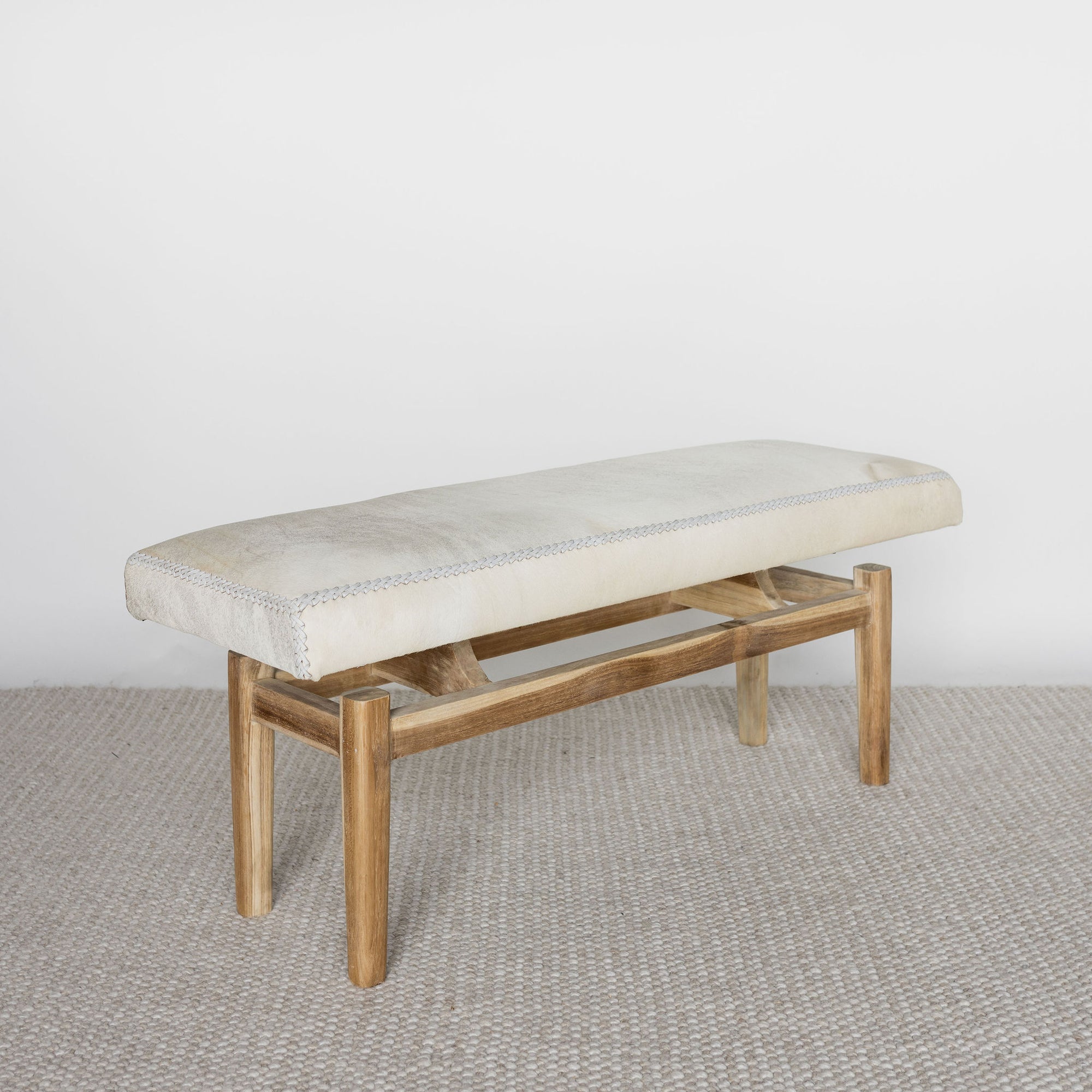 angled view of a cream cowhide bench seat ottoman 