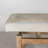 close up end view showing the stitching on a cream coloured cowhide bench seat ottoman