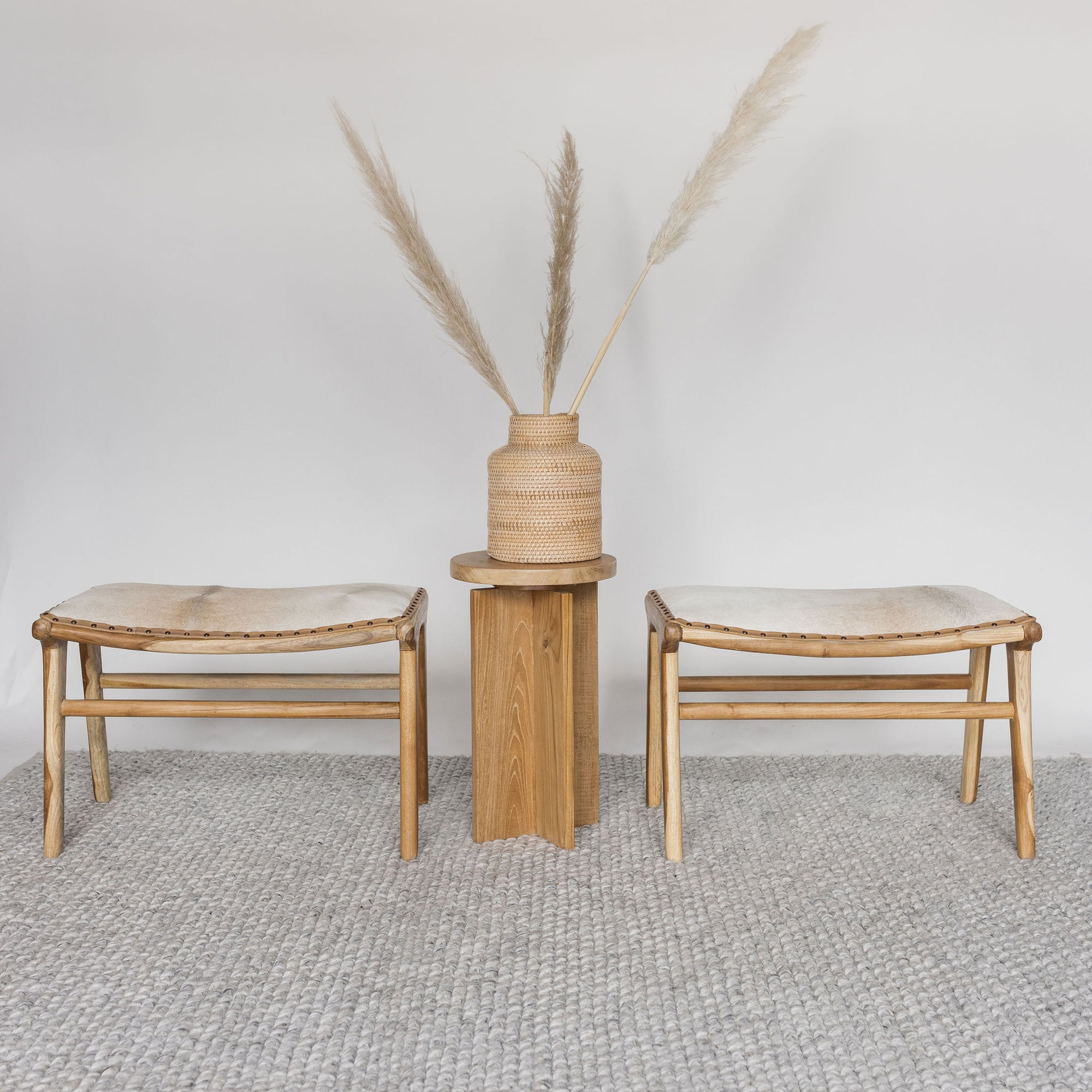 small cowhide bench seats with a wooden side table on a looped rug