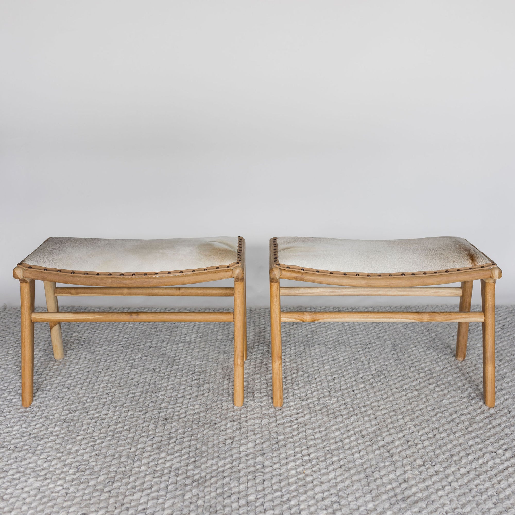 set of two small cowhide stools for the end of bed seating