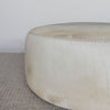 close up view of the stitching on the cream side of a cream and grey cowhide round ottoman from corcovado