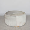 front view of a cream and grey cowhide round ottoman from corcovado