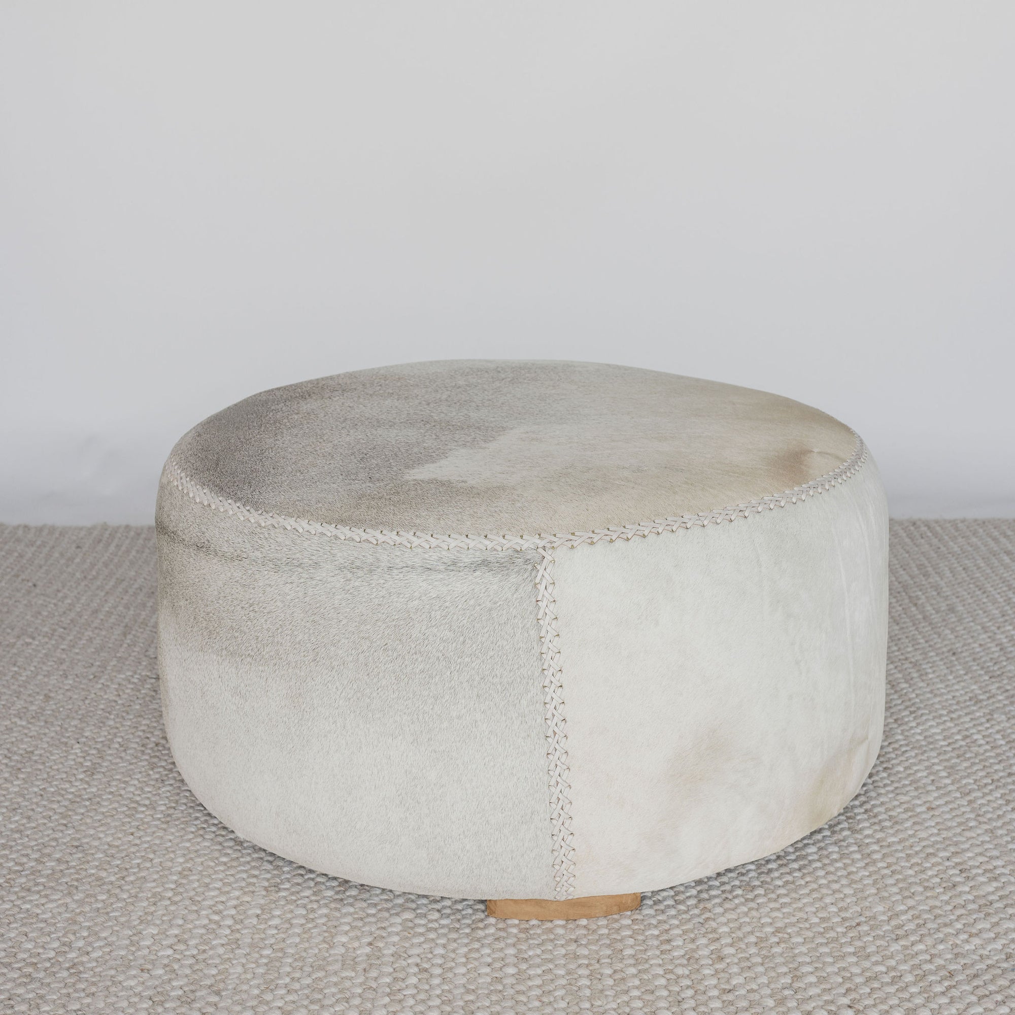 front view of a cream and grey cowhide round ottoman from corcovado 