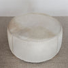 top down view showing the leather stitching on the cream coloured light cowhide round ottoman coffee table