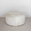 cream coloured light cowhide round ottoman coffee table on a looped wool rug