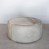 side view of the round cowhide ottoman pouff with distinctive natural markings on the top of the hide.