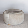 front view of a charcoal grey round cowhide ottoman coffee table