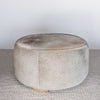 another front angled view of a charcoal grey round cowhide ottoman coffee table