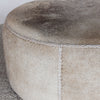 close up view showing the leather stitching detail of the charcoal grey round cowhide ottoman coffee table