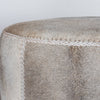 close up showing the leather stitching on the charcoal grey round cowhide ottoman coffee table