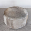 top down view of a charcoal grey round cowhide ottoman coffee table