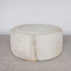 side view of a cream with caramel round cowhide ottoman from corcovado