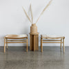 small rattan woven basket vase from corcovado furniture alongside 2 cowhide bench seats and a pillar wooden side table