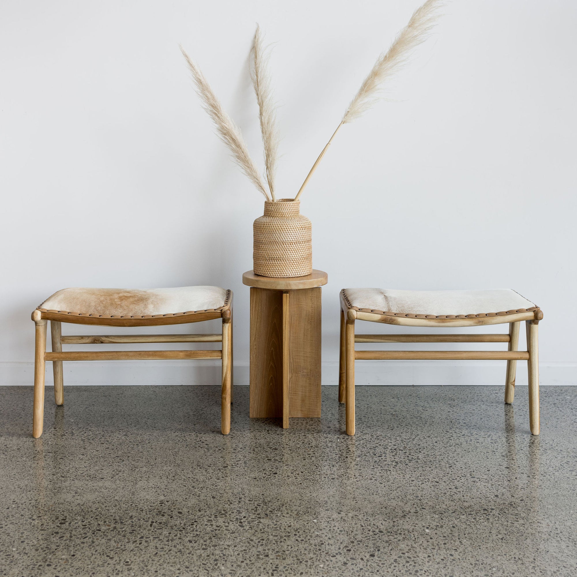 small rattan woven basket vase from corcovado furniture alongside 2 cowhide bench seats and a pillar wooden side table 