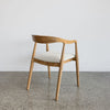 back view of a wooden dining chair with a curved back which is upholstered in fibreguard fabric by Corcovado