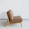 side view of an oversized lounge chair in tan leather like fabric on a teak wood frame