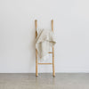 off white wool blend throw with off white fringing styled on a natural bamboo ladder