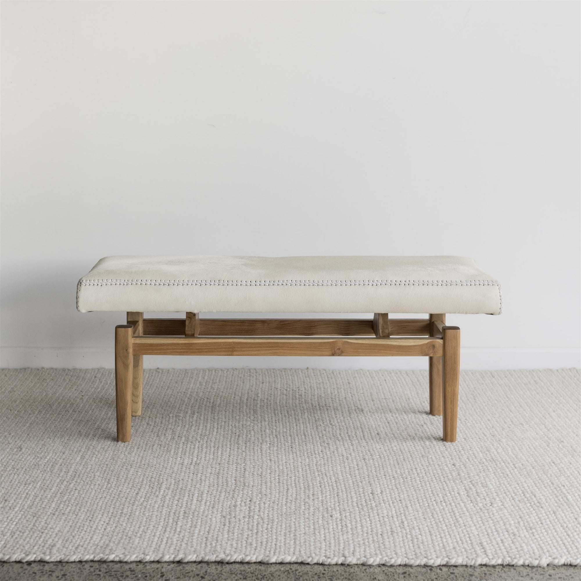 cowhide bench seat with wood base from corcovado furniture in light cream white tones