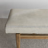 close up on one end of the cowhide bench seat with wood base from corcovado furniture in light cream white tones