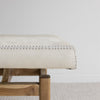 side view of the cowhide bench seat with wood base from corcovado furniture in light cream white tones