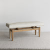 angled view of the cowhide bench seat with wood base from corcovado furniture in light cream white tones