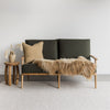 fenugreek linen cushion on a green sofa with a caramel icelandic sheepskin